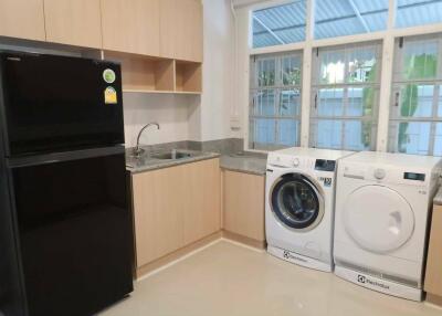 Modern kitchen with black refrigerator, washing machine, and dryer