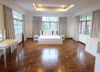 Spacious bedroom with wooden flooring, large windows, and a central bed.