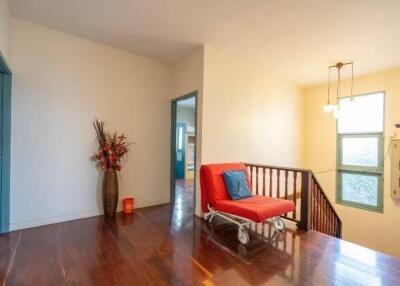 Bright hallway with wooden floor, flower vase, couch and wall-mounted lights