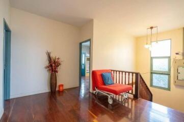 Bright hallway with wooden floor, flower vase, couch and wall-mounted lights