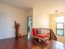 Bright hallway with wooden floor, flower vase, couch and wall-mounted lights