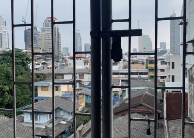 View of city skyline and neighboring buildings from a balcony with safety bars