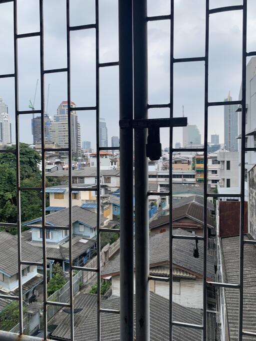 View of city skyline and neighboring buildings from a balcony with safety bars