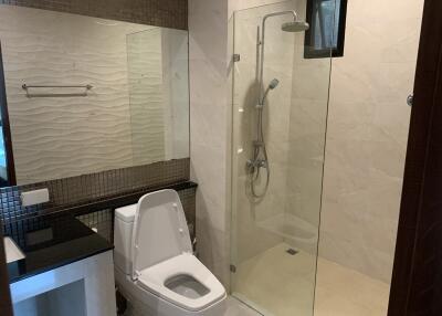 Modern bathroom with large mirror, toilet, and glass-enclosed shower