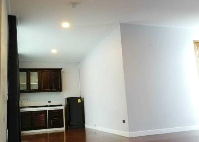 Spacious living room with adjacent kitchen featuring wooden flooring and modern lighting