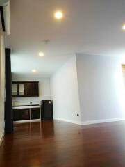 Spacious living room with adjacent kitchen featuring wooden flooring and modern lighting