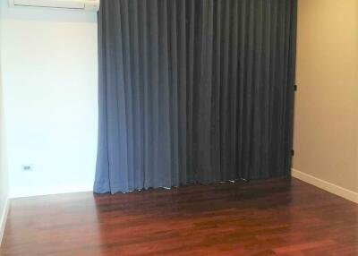 Empty bedroom with wooden floor and dark curtains