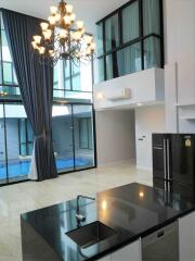 Modern living area with high ceilings and large windows overlooking a courtyard pool.