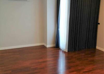 Spacious bedroom with wooden flooring and natural light