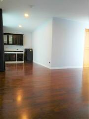 Spacious living area with hardwood floors and adjacent kitchen