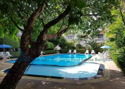 Swimming pool area with trees and lounge chairs