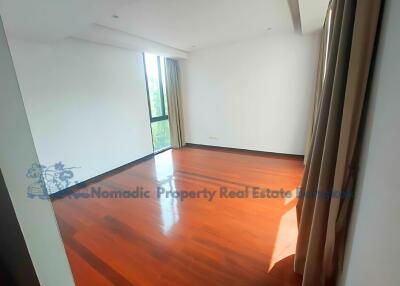 Spacious bedroom with wooden floors and large window