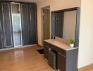 Modern bedroom with wooden floor, built-in wardrobes, and a vanity table