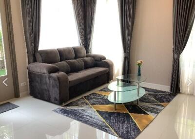 Well-lit living room with a grey couch and modern glass coffee table