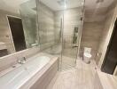 Modern bathroom with glass shower, bathtub, and toilet