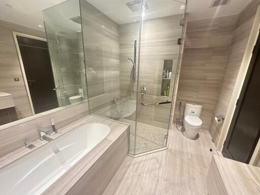 Modern bathroom with glass shower, bathtub, and toilet