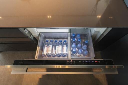 Open drawer in modern kitchen with refrigerator drawer and bottled water