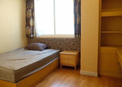 Bedroom with built-in shelves, window, and wooden flooring