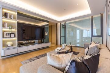 Modern living room with large TV, couch, and glass walls