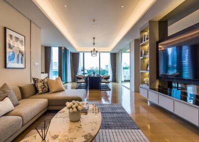 Modern living room with a sectional sofa, coffee table, television, and dining area in the background