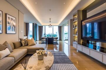 Modern living room with a sectional sofa, coffee table, television, and dining area in the background