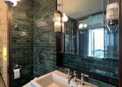 Modern bathroom with green tiled walls and large mirror