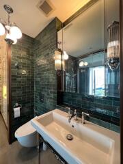 Modern bathroom with green tiled walls and large mirror