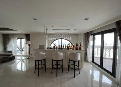 Spacious living area with a modern bar setup and floor-to-ceiling windows