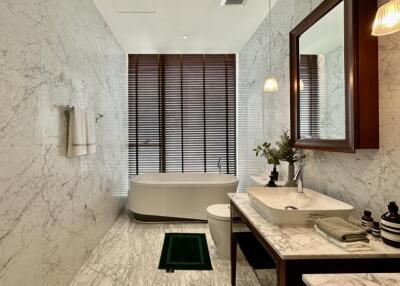 Modern bathroom with marble walls and floor, featuring a freestanding bathtub and stylish sink area