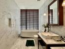 Modern bathroom with marble walls and floor, featuring a freestanding bathtub and stylish sink area