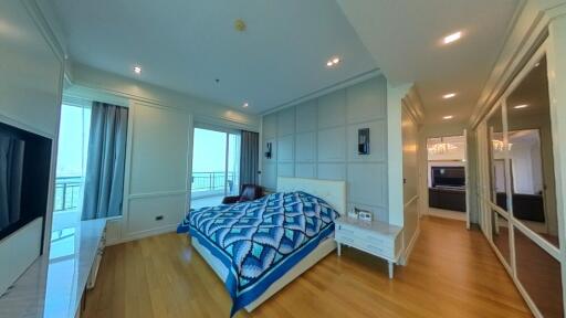 Spacious bedroom with bed, nightstands, and large windows