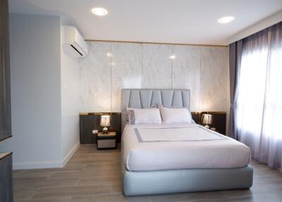 Modern bedroom with a double bed, side tables, and large window with curtains