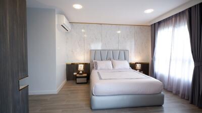 Modern bedroom with a double bed, side tables, and large window with curtains