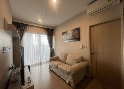 Compact modern living room with a sofa, TV, air conditioner, and large window.