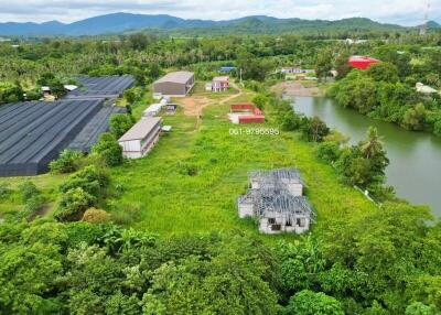 Aerial view of a property with buildings, greenery, and a water body