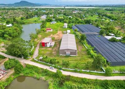 Aerial view of a rural property with buildings, ponds, and surrounding greenery