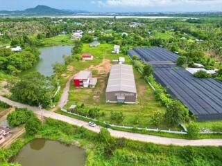 Aerial view of a rural property with buildings, ponds, and surrounding greenery