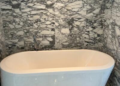 A modern bathroom with marble tiles and a freestanding bathtub