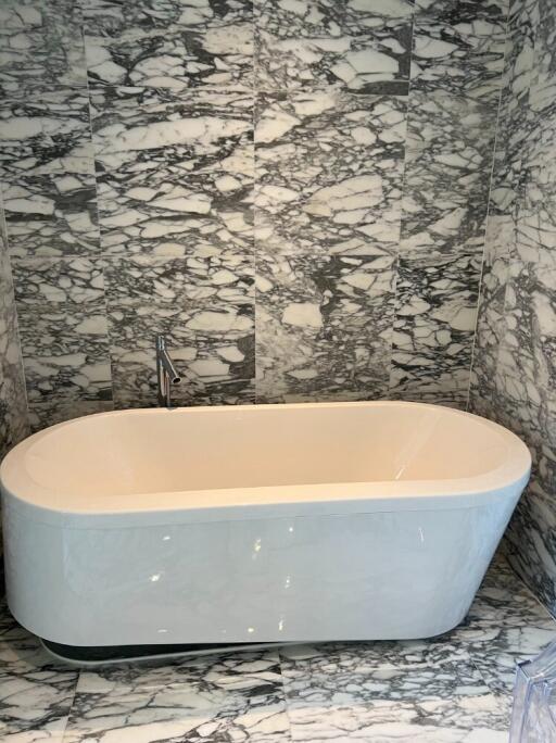 A modern bathroom with marble tiles and a freestanding bathtub