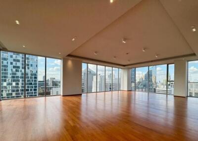 Spacious living area with wooden floors and large windows providing city views