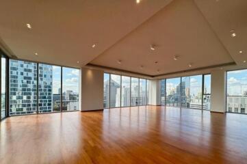 Spacious living area with wooden floors and large windows providing city views