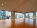 Spacious living area with wooden floors and large windows providing city views