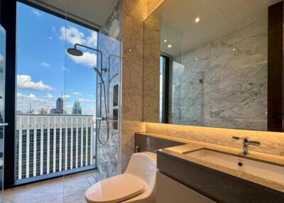 Modern bathroom with large glass shower, vanity, and city view