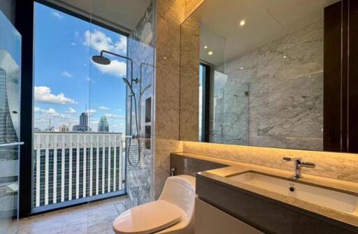 Modern bathroom with large glass shower, vanity, and city view