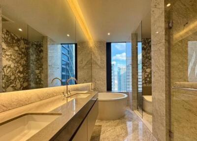 Modern bathroom with a large tub, double sinks, and marble finishes