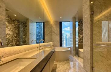 Modern bathroom with a large tub, double sinks, and marble finishes