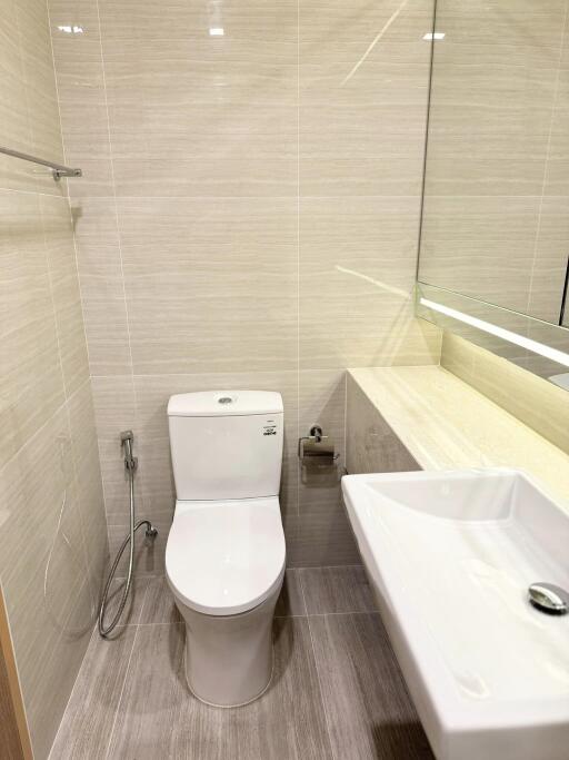 Modern bathroom with toilet, bidet spray, and sink