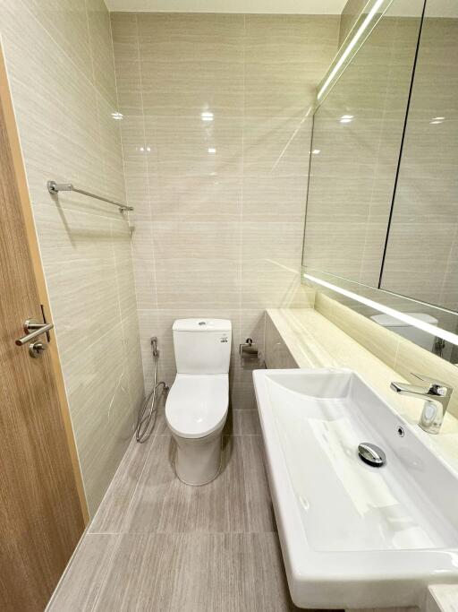 Modern bathroom with sink, toilet, and large mirror