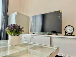 Modern living room with TV, clock, and decorative plant