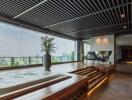 Modern living room with glass walls, pool, and city view